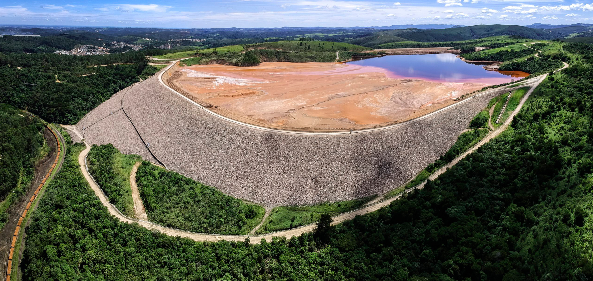 A vista aérea de uma barragem de rejeitos com uma vegetação em volta.